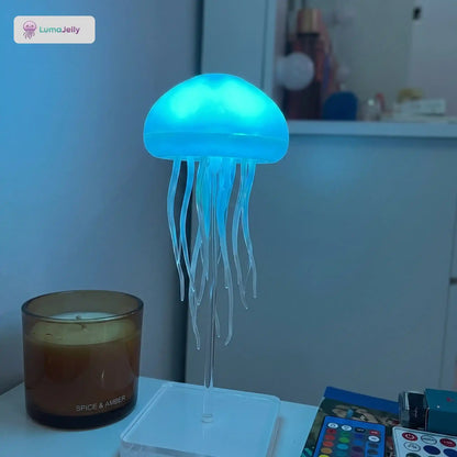 Lámpara de medusas LumaJelly™ en color azul cian con control remoto y base de pedestal acrílica, ideal para decorar mesitas de noche y crear ambientes relajantes.